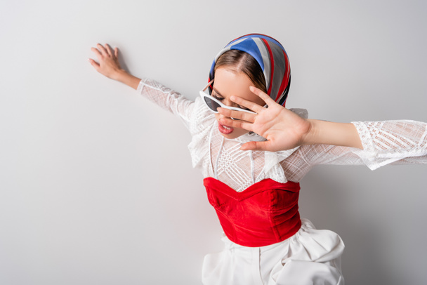 high angle view of young trendy woman in headscarf and sunglasses gesturing on white - Foto, Imagem