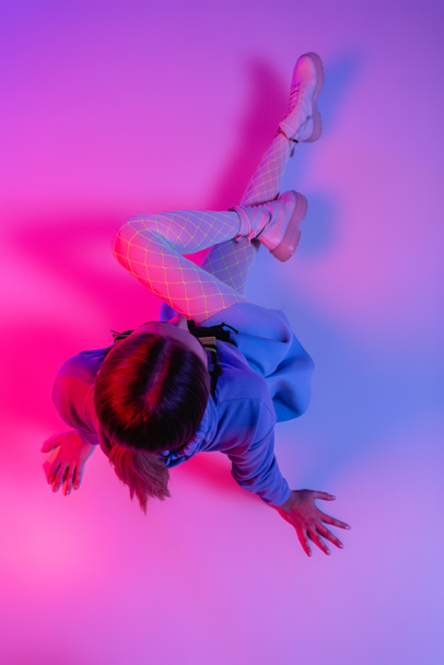 top view of stylish woman in trendy outfit sitting on purple and pink - 写真・画像