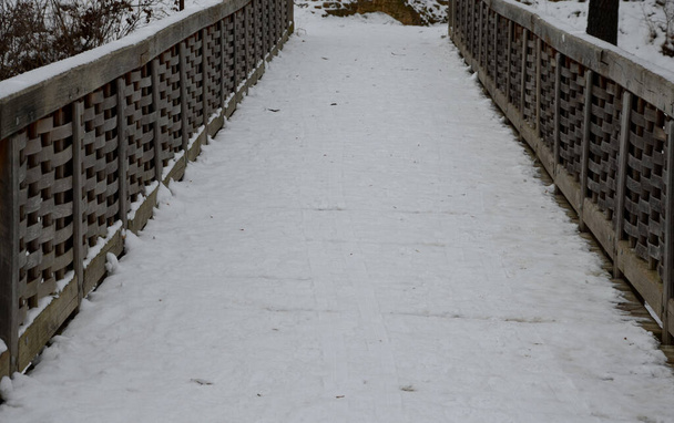 Μεσαιωνικό ξύλο βελανιδιάς, βιδωμένο. Μια γέφυρα πάνω από μια τάφρο που χτίστηκε σύμφωνα με ένα μοντέλο περιόδου. Ξύλινες γέφυρες θα μπορούσαν να καούν ή να καούν γρήγορα αν απειλούνταν το κάστρο. Το χειμώνα με χιόνι. - Φωτογραφία, εικόνα