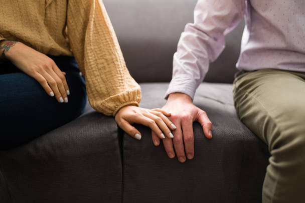 Fiatal nő és férfi ül a kanapén, és megérinti a kezét. A szerelmes pár flörtöl az első randin. - Fotó, kép