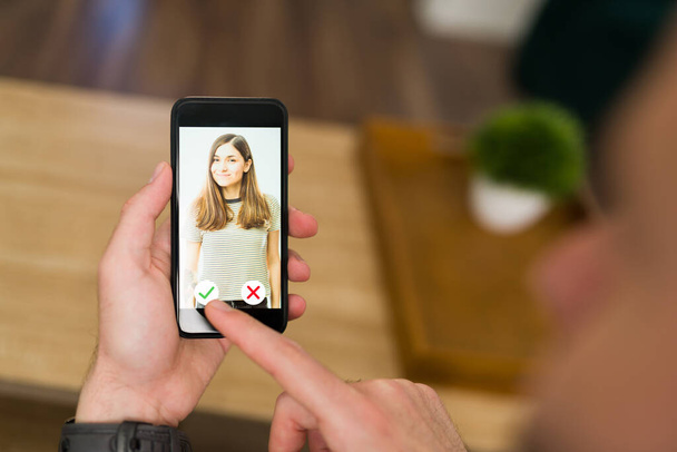 Close-up van een man met een smartphone en op zoek naar liefde en een vriendin op een dating app. Guy scrollen profiel foto 's op een relatie website  - Foto, afbeelding