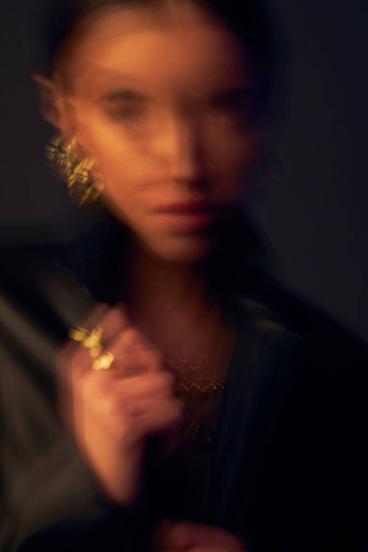 portrait with double exposure of a dark-eyed beautiful girl with black hair, professional make-up, dressed in a black jacket, she has gold jewelry on her arm and ears - Zdjęcie, obraz