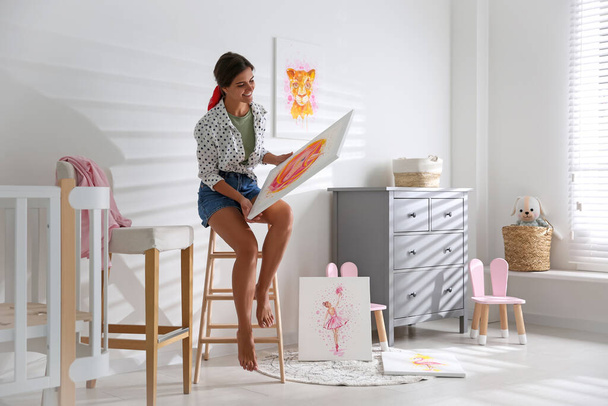 Decorator with picture on ladder in baby room. Interior design - Foto, afbeelding