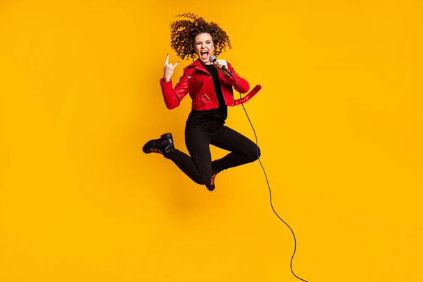 Full length body size view of nice cheerful ecstatic cool crazy wavy-haired girl jumping singing showing horn sign isolated on yellow color background - Foto, afbeelding