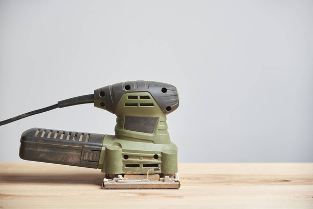 Electric sander on a pine wood plank, carpentry tool. Image with copy space. - Photo, Image
