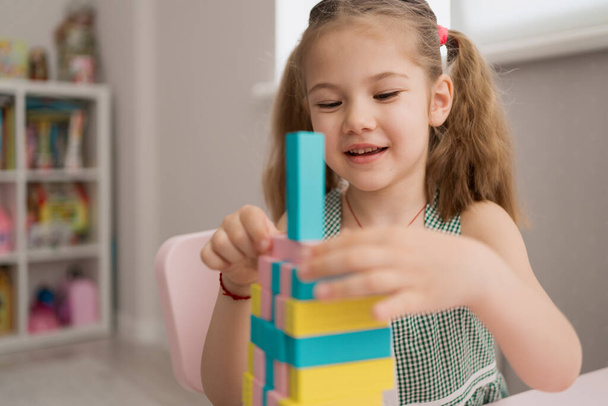 Beautiful caucasian girl playing with wooden multi-colored blocks - Foto, afbeelding