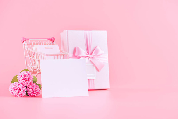 Mother's Day holiday gift design concept, pink carnation flower bouquet with wrapped gift box isolated on pink background, copy space. - Foto, afbeelding