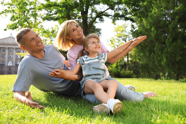 Happy parents with their child having fun on green grass. Spending time in nature - Fotografie, Obrázek