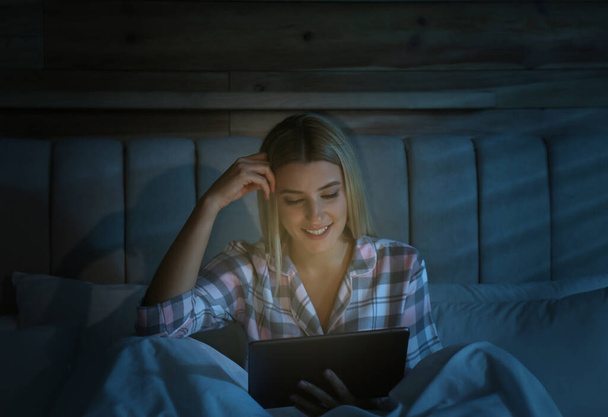 Young woman using tablet in bed at night. Sleeping disorder problem - Φωτογραφία, εικόνα