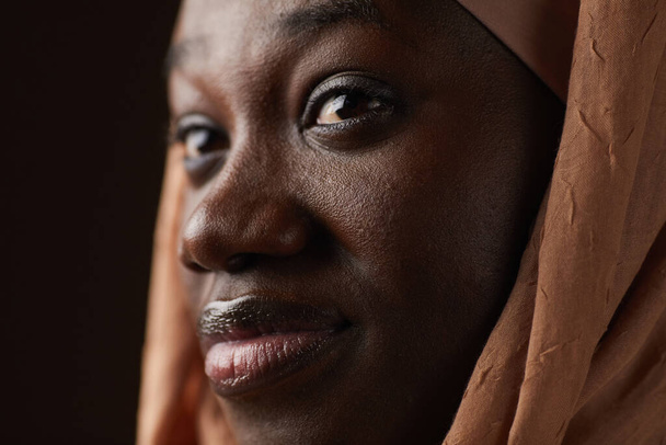 Extreme close up πορτραίτο μιας Αφρο-Αμερικανίδας που φοράει μαντίλα και κοιτάζει αλλού ενώ ποζάρει στο στούντιο - Φωτογραφία, εικόνα