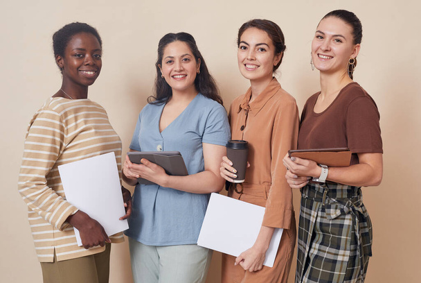 Multiethnische Gruppe von vier jungen Geschäftsfrauen, die im Büro an der Wand stehen und in die Kamera schauen - Foto, Bild