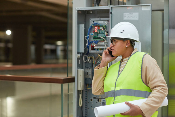 Widok z boku portret kobiety inżyniera mówiącej przez smartfona podczas kontroli placu budowy, przestrzeń kopiowania - Zdjęcie, obraz