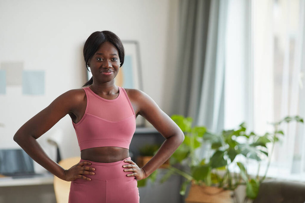 Натисніть портрет усміхненої афро-американської жінки в рожевому спортивному лаві, насолоджуючись тренуванням вдома, копіюйте простір - Фото, зображення