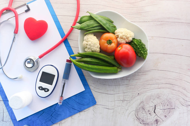  cukorbetegséget mérő eszközök és friss zöldség az asztalon  - Fotó, kép
