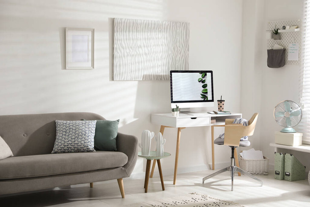 Comfortable office chair near desk with modern computer indoors - Foto, Bild