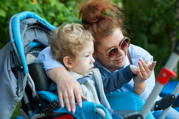 Madre con hijo discapacitado caminando al aire libre con andador, equipo de movilidad médica - Foto, imagen