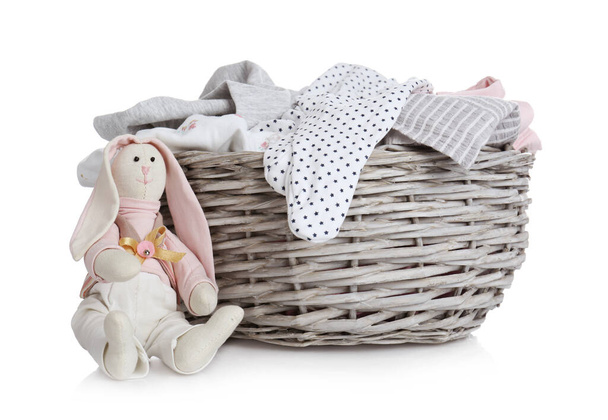 Wicker basket with baby clothes and bunny on white background - Valokuva, kuva