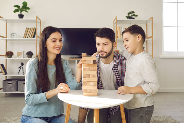 Happy family with child playing jenga while enjoying quiet indoor activities together - Foto, Imagen