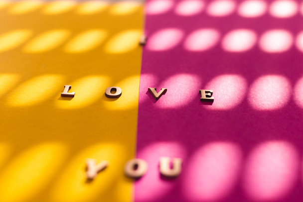 メッセージ私はあなたが木製の手紙で綴った愛し,鮮やかな黄色とピンクの色の背景の間に分割  - 写真・画像