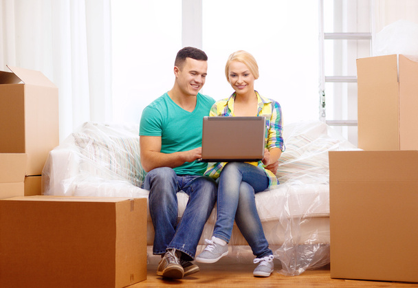 Couple relaxing on sofa with laptop in new home - Foto, Bild