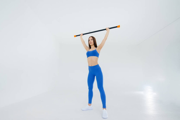 Sexy young girl performs sports exercises on a white background. Fitness, healthy lifestyle - Valokuva, kuva
