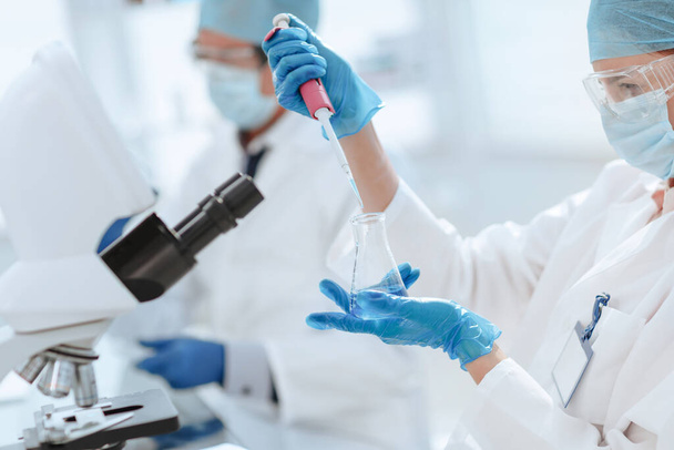 close up. female scientist examining a liquid in a laboratory flask . - 写真・画像