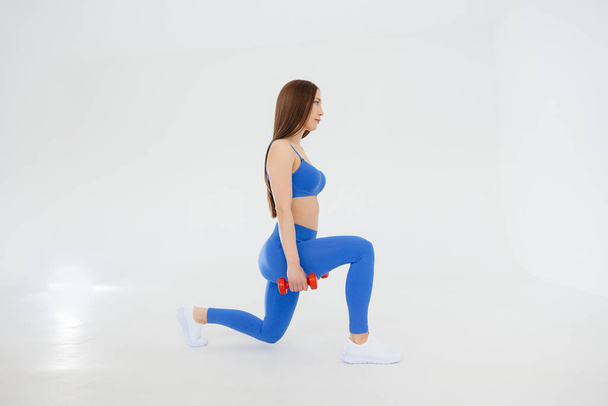 Sexy young girl performs sports exercises on a white background. Fitness, healthy lifestyle - Fotó, kép