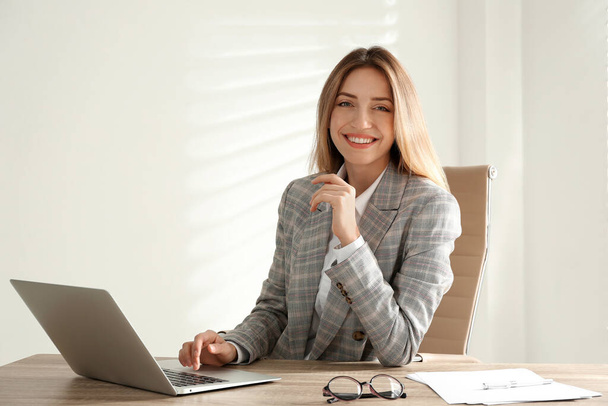 Portrait of beautiful young businesswoman with laptop at table in office - Foto, afbeelding