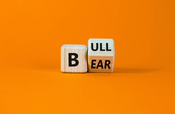 Symbol for a positive trend at the stock market. Turned a cube and changed the word 'bear' to 'bull'. Beautiful orange background. Business and bear or bull concept. Copy space. - Foto, Bild
