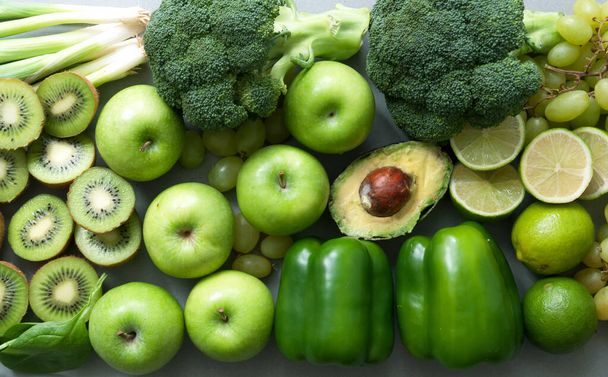 Healthy organic green fruits and vegetables closeup incluing broccoli, apples, kiwi, lime, peppers, and avocado - Foto, imagen