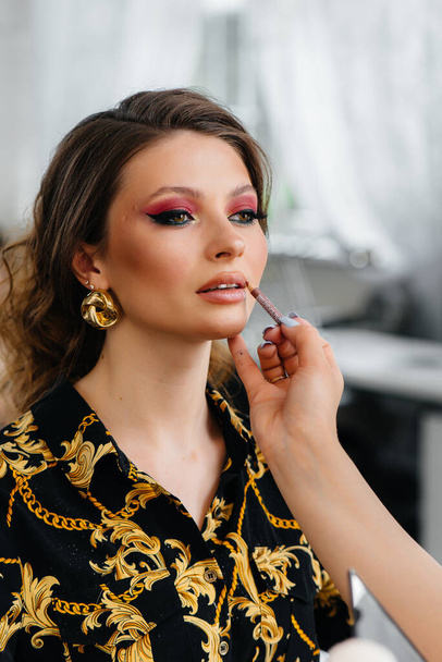 In a beautiful, modern beauty salon, a professional makeup stylist makes makeup for a young girl. Beauty, and fashion - Fotografie, Obrázek