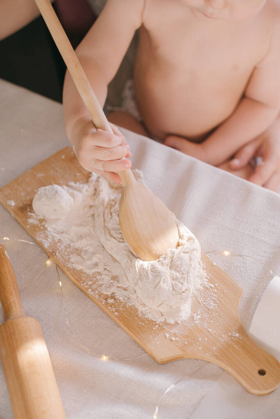 Children's hands in flour prepare cookies on a table - Фото, изображение