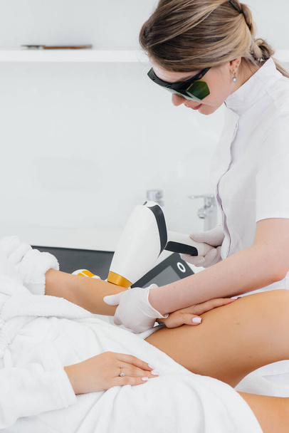 A beautiful young girl will undergo laser hair removal with modern equipment in a Spa salon. Beauty salon. Body care - Photo, Image