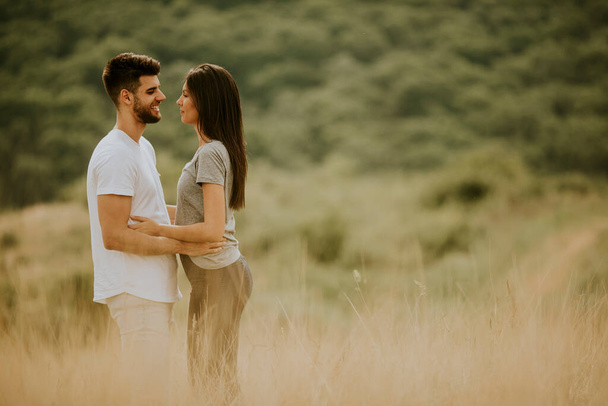 Happy young couple in love walking through grass field on a summer day - Photo, Image
