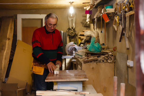Ξυλουργός κάνει τη δουλειά του στο εργαστήριο ξυλουργικής. - Φωτογραφία, εικόνα