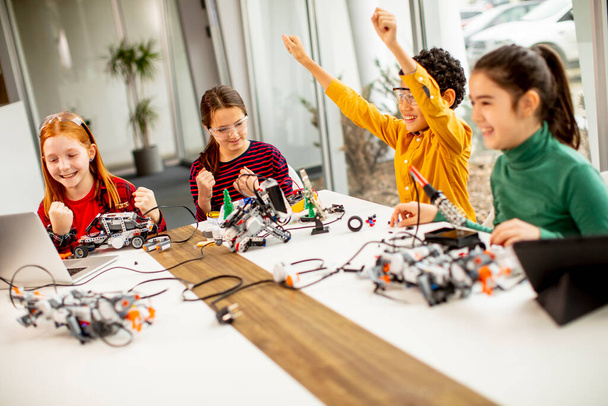 Gruppo di bambini felici che programmano giocattoli elettrici e robot in classe di robotica - Foto, immagini