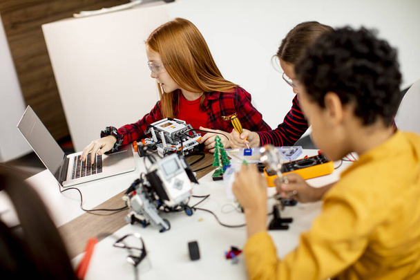 Grupo de niños felices programando juguetes eléctricos y robots en el aula de robótica - Foto, imagen