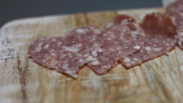 Embutido de salami en rodajas italiano fresco en una tabla de cortar de madera, formas de corazón de salchicha de salami de Milán. Preparación de pizza en forma de corazón para el Día de San Valentín para un ser querido. Vídeo 4K - Metraje, vídeo
