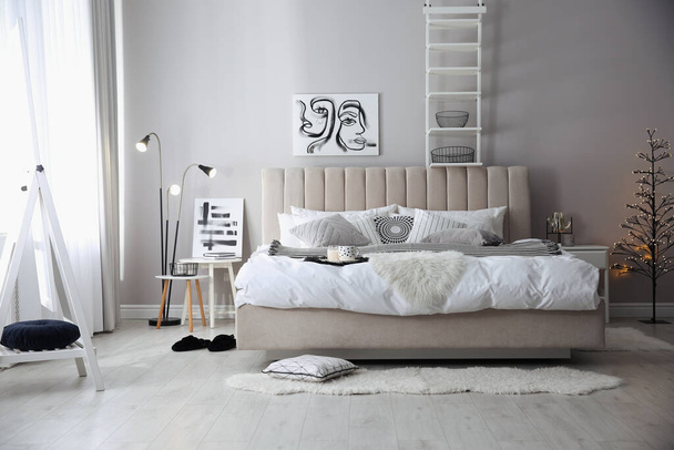 Cozy bedroom interior with decorative tree and beautiful pictures - Fotoğraf, Görsel