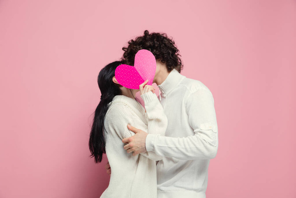Young, beautiful couple in love on pink studio background. Valentines Day, love and emotions concept - Foto, Imagem