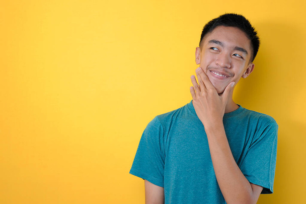 Muotokuva onnellinen nuori aasialainen mies hymyilee katso kopiotilaa, eristetty keltaisella taustalla - Valokuva, kuva