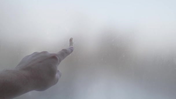 a kéz szomorú arcot fest a ködös üvegre. A magány és a szomorúság szimbóluma - Felvétel, videó