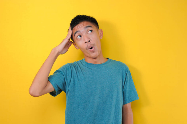 Portret jonge aziatische man met verrassende expressie kijken naar een kopieerruimte, geïsoleerd op gele achtergrond - Foto, afbeelding