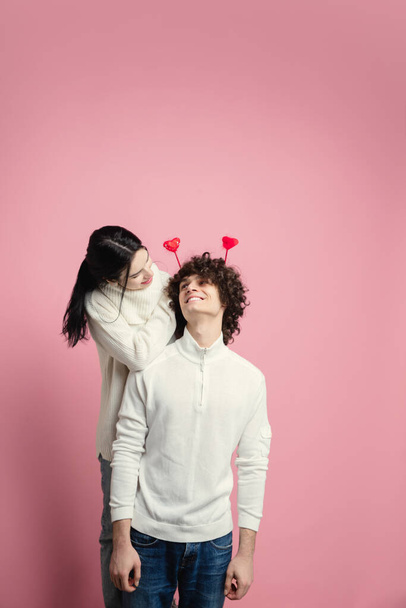 ピンク色のスタジオの背景に愛の若い、美しいカップル。バレンタインデー、愛と感情の概念 - 写真・画像