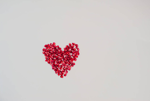  Herz aus roten Granatapfelbeeren auf weißem Hintergrund, Draufsicht. Prävention von Schlaganfällen, Gesundheitsfürsorge. Valentinstag - Foto, Bild