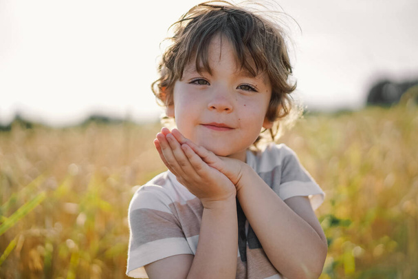 Mały chłopiec modlący się na polu pszenicy. - Zdjęcie, obraz