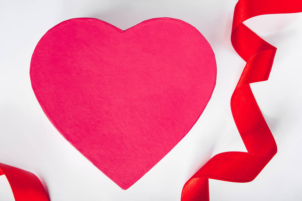Valentine's day concept. Red silk ribbon and heart on white background. - Photo, Image