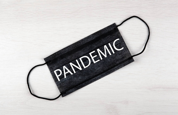 musta lääketieteellinen naamio, jossa merkintä pandemia pöydällä - Valokuva, kuva