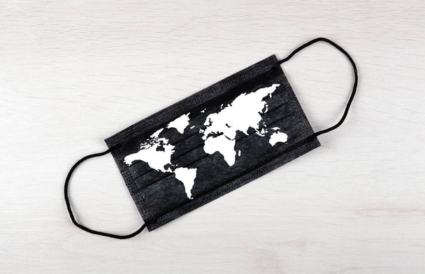 máscara médica negro con mapa del mundo sobre la mesa  - Foto, imagen
