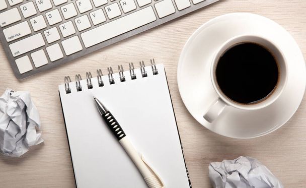 mesa de trabajo, una taza de café, un cuaderno con una pluma y una vista superior de papel arrugado - Foto, Imagen